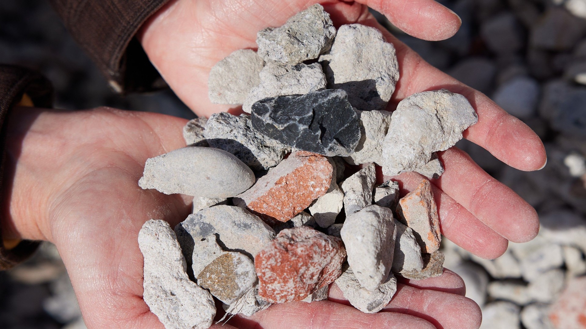 Hände halten Bauschutt aus Mauerwerk, Beton und Keramik